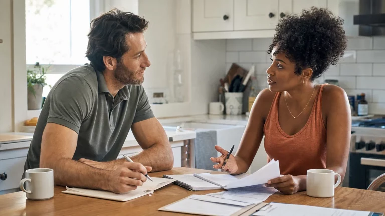 Two adult partners comparing separate financial plans during an open, nonjudgmental conversation.